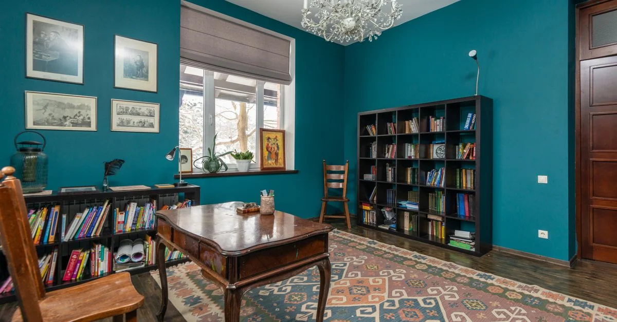 Charmant bureau de style vintage avec des murs bleus, du mobilier en bois et un chandelier classique.