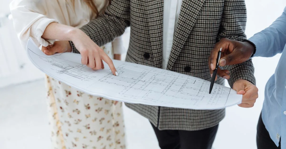 Des adultes examinant des plans de sol schématiques détaillés à l'intérieur pour un nouveau bâtiment.