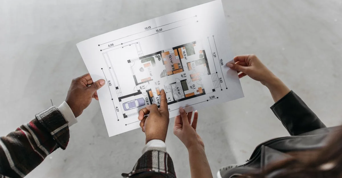 Deux personnes examinant des plans architecturaux et mesurant un nouveau design de maison.