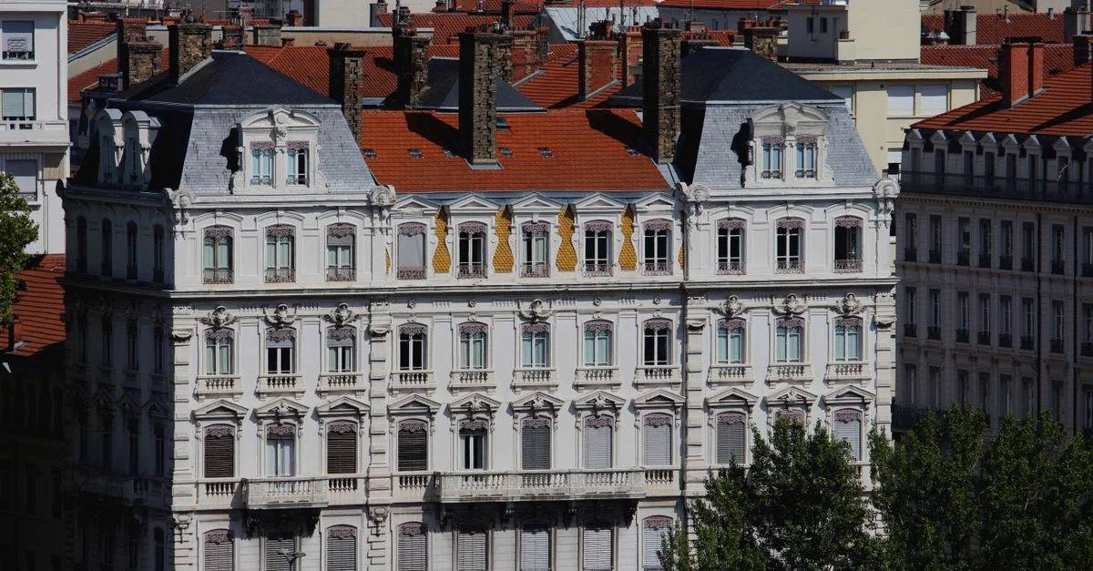 Façade blanche ornée d'un bâtiment historique avec des tuiles de toiture rouges en Europe.