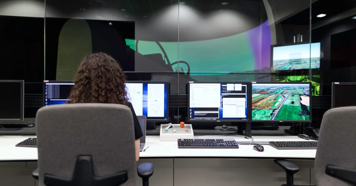Ingénieure gérant plusieurs écrans lors d'une simulation technologique dans une salle de contrôle.