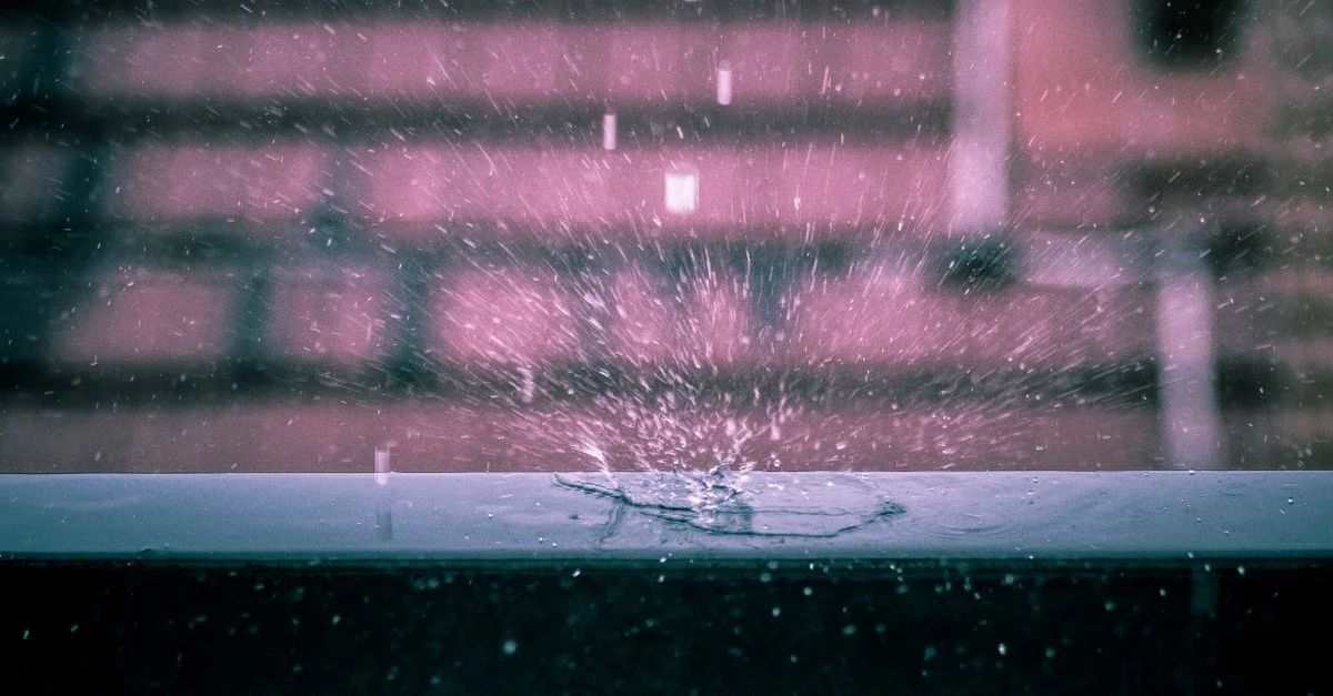 Capture dramatique d'une goutte de pluie éclaboussant une surface avec un fond urbain flou.