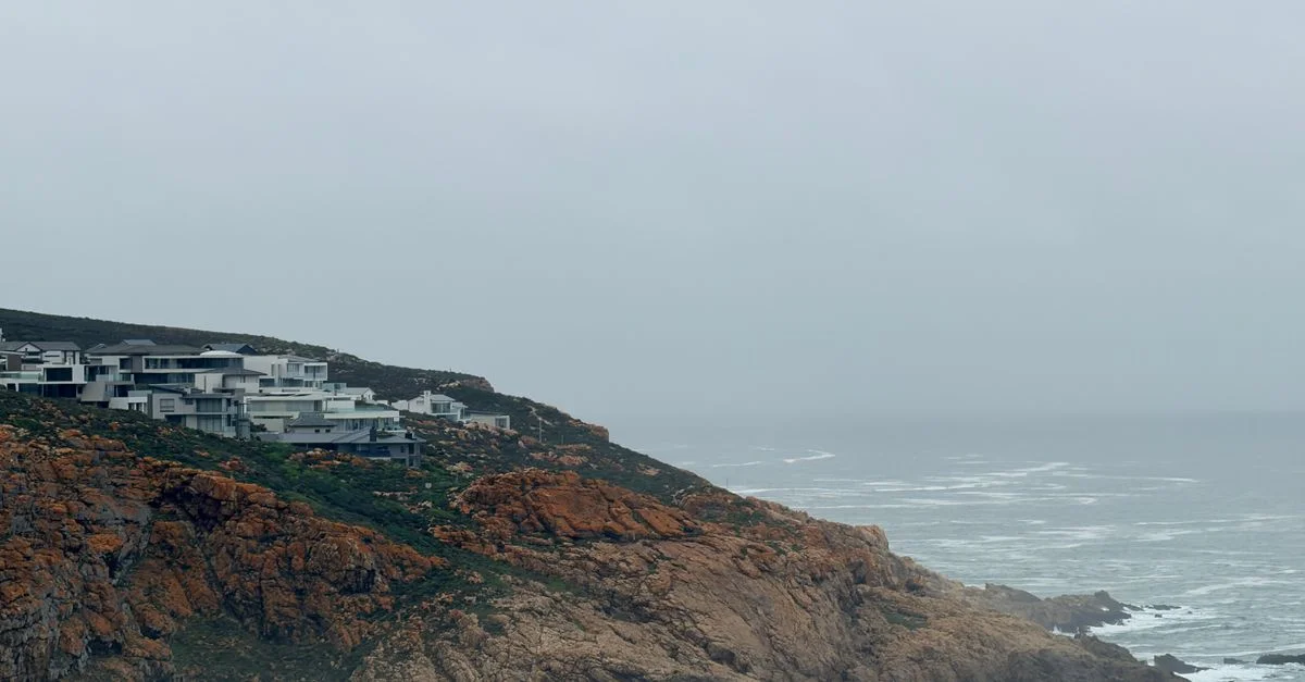 Vue pittoresque de maisons modernes perchées sur des falaises rocheuses surplombant un océan brumeux à George, en Afrique du Sud.