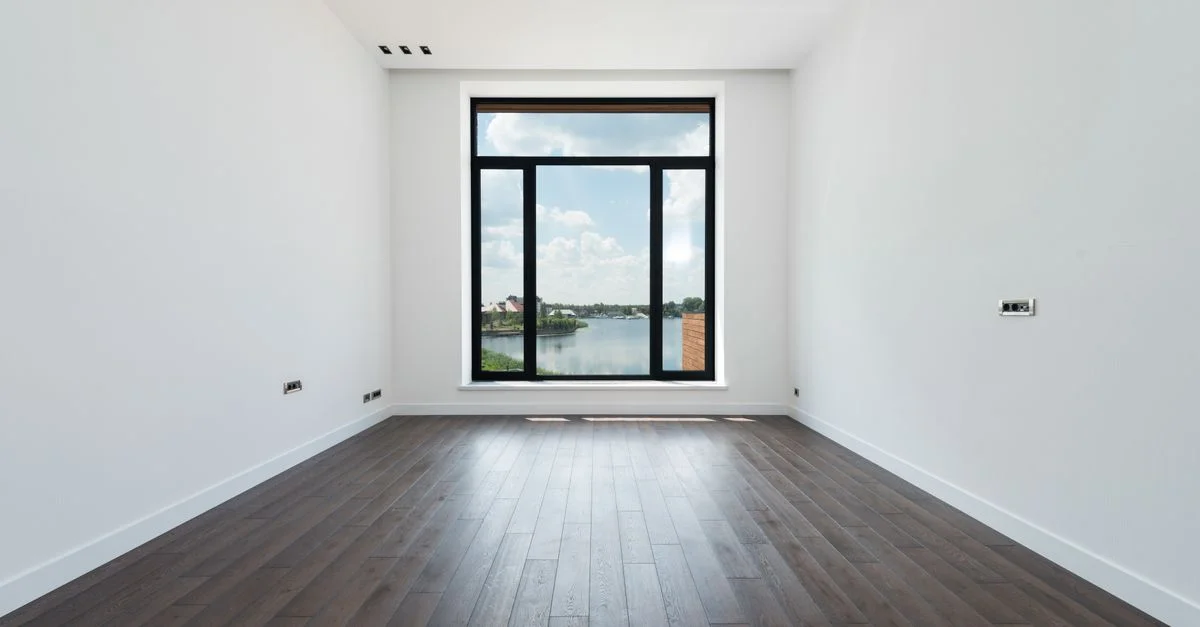 Chambre moderne spacieuse avec un sol en bois et une grande fenêtre offrant une vue extérieure pittoresque.