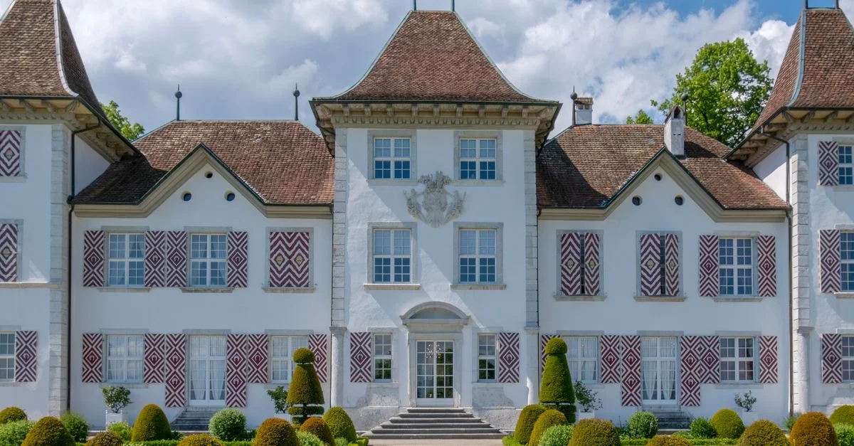 Magnifique manoir de style européen avec un design symétrique et des jardins luxuriants sous un ciel d'été lumineux.