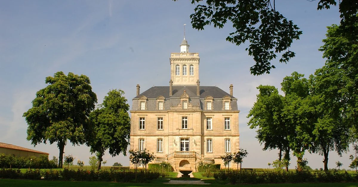 Un majestueux château avec des jardins luxuriants et un ciel bleu, capturant l'architecture classique.