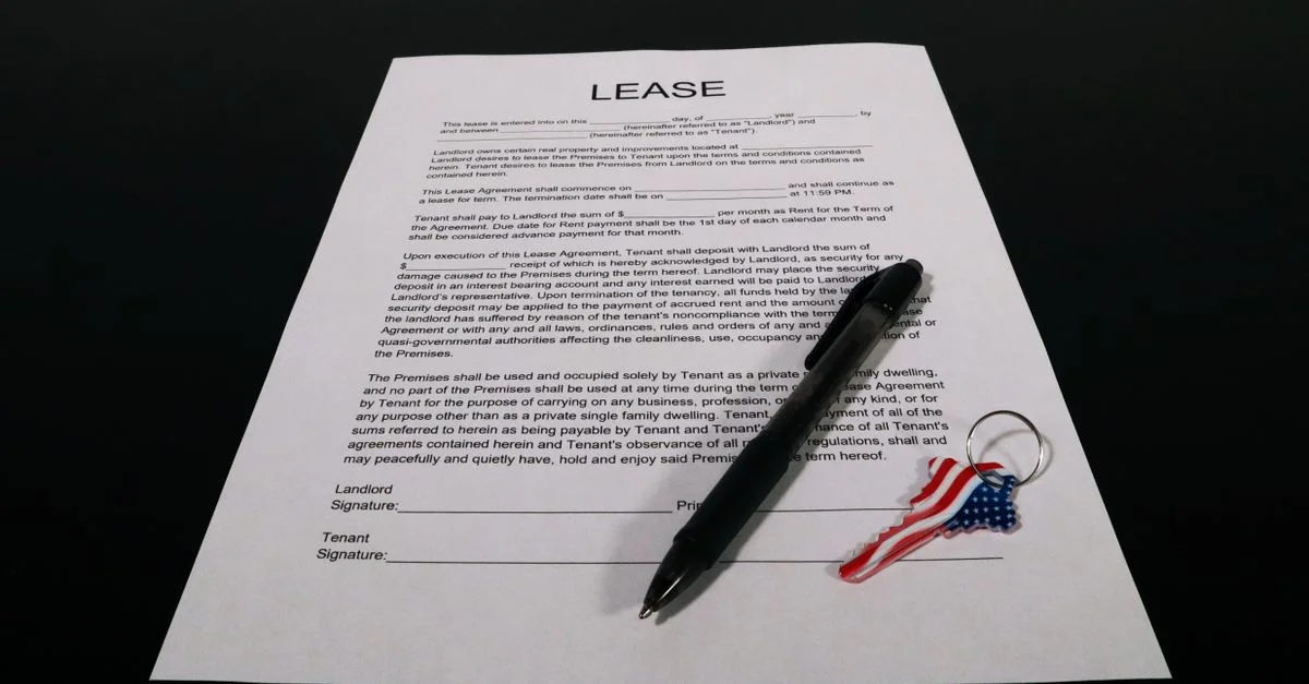Document de contrat de location avec stylo et porte-clés drapeau américain sur une table noire.