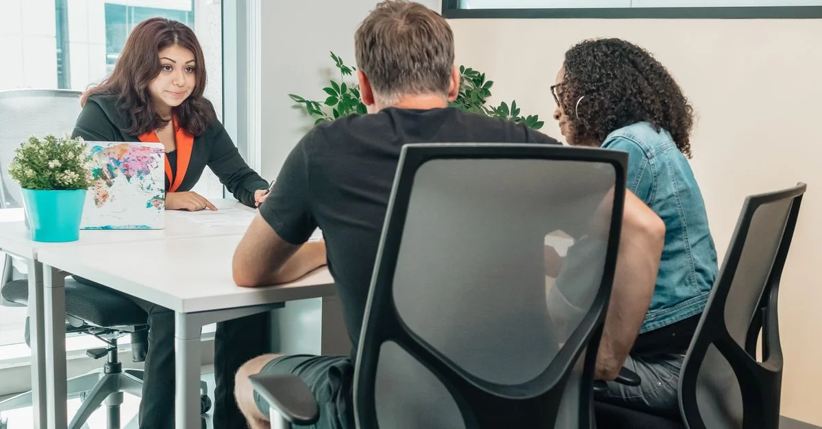Un conseiller d'affaires consulte des clients dans un bureau moderne, favorisant le travail d'équipe et la coopération.
