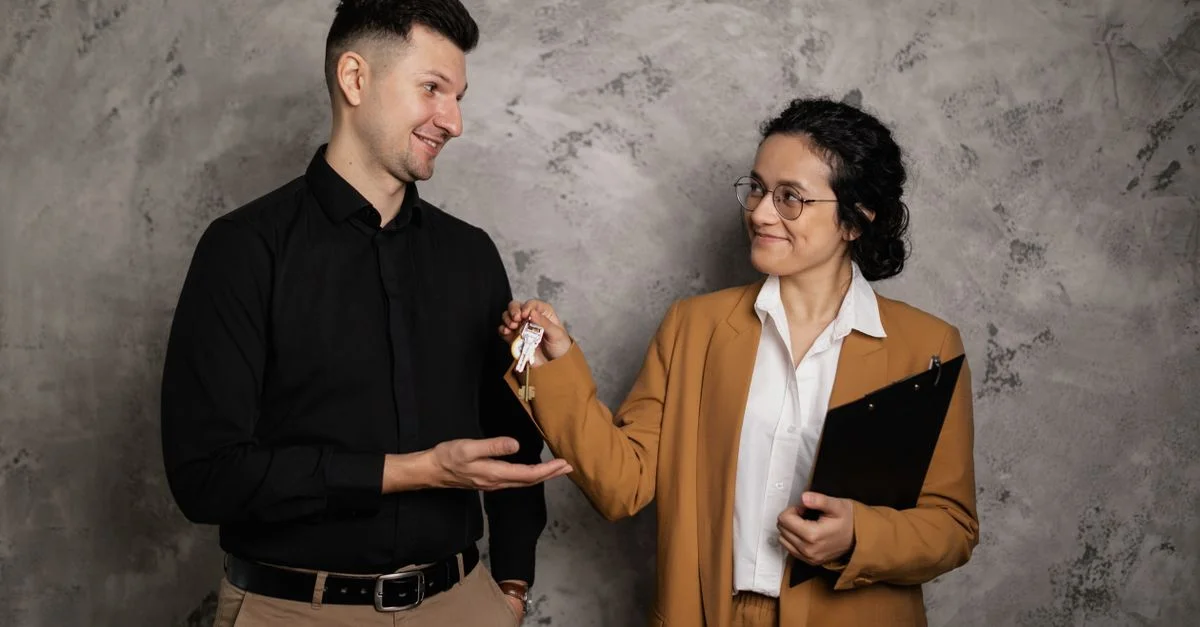 Un agent immobilier souriant remet les clés de la maison à un nouveau propriétaire dans un cadre intérieur.