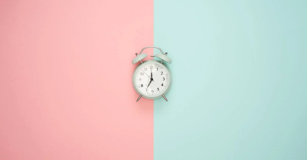 Une horloge ronde vintage sur un fond dégradé pastel rose et bleu.