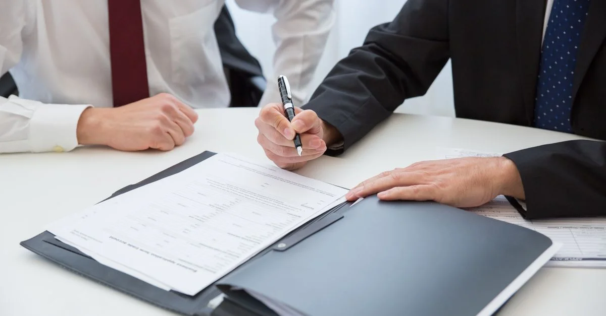 Deux professionnels signant un contrat lors d'une réunion d'affaires dans un bureau.