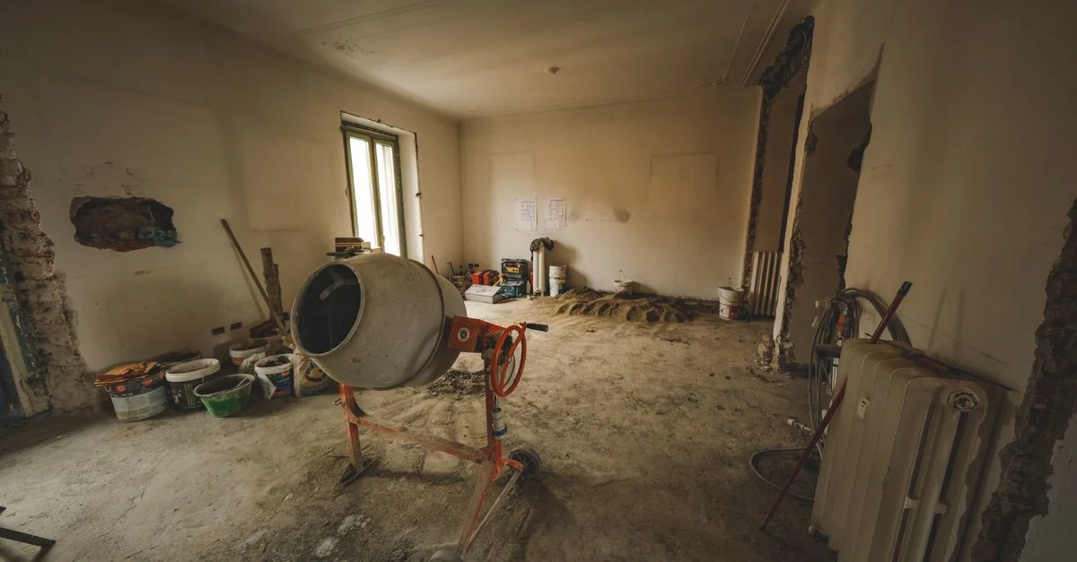 Salle vide avec une bétonnière et des outils, idéale pour des concepts de rénovation.